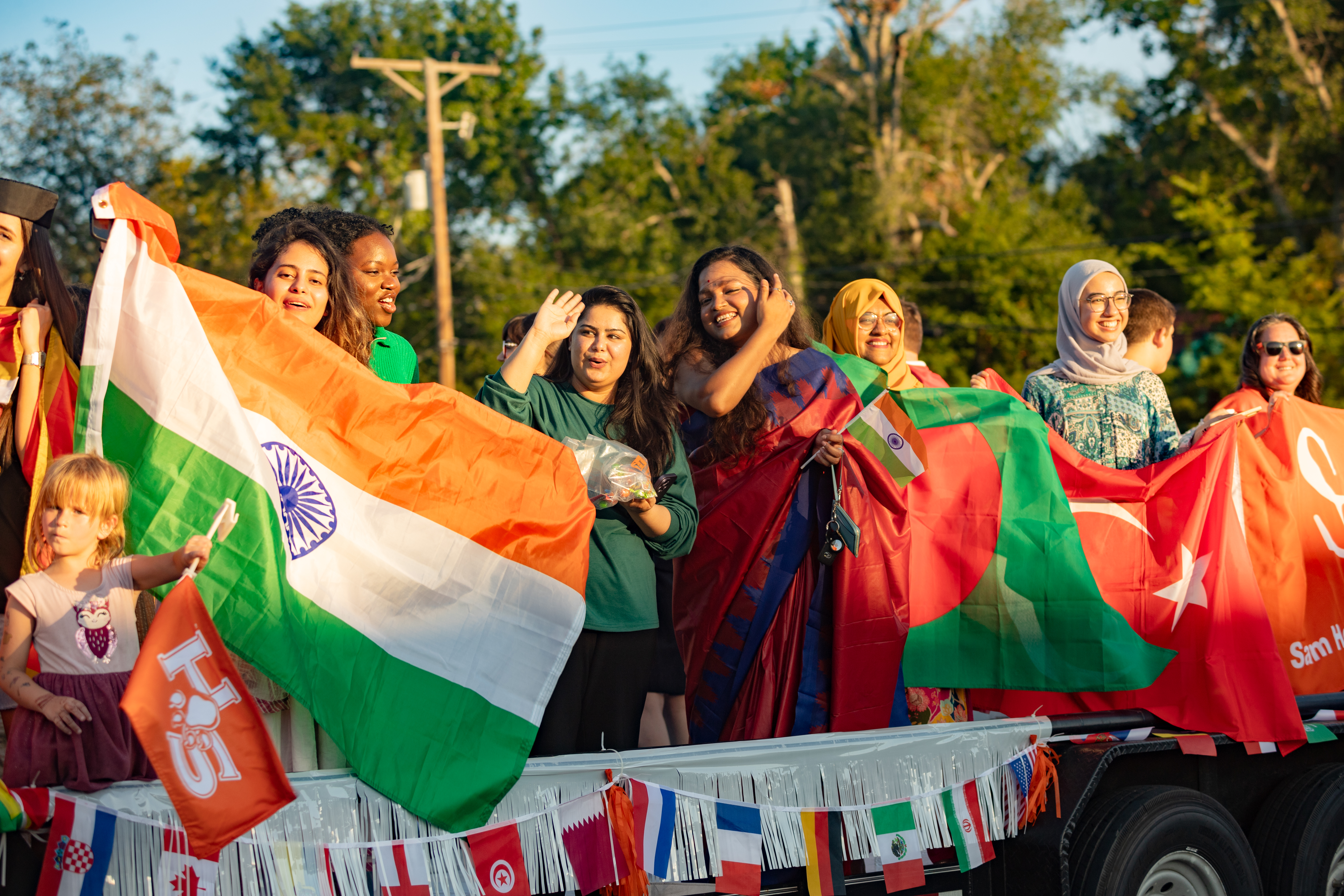 SHSU international students holding their home country flag during Home Coming parade.