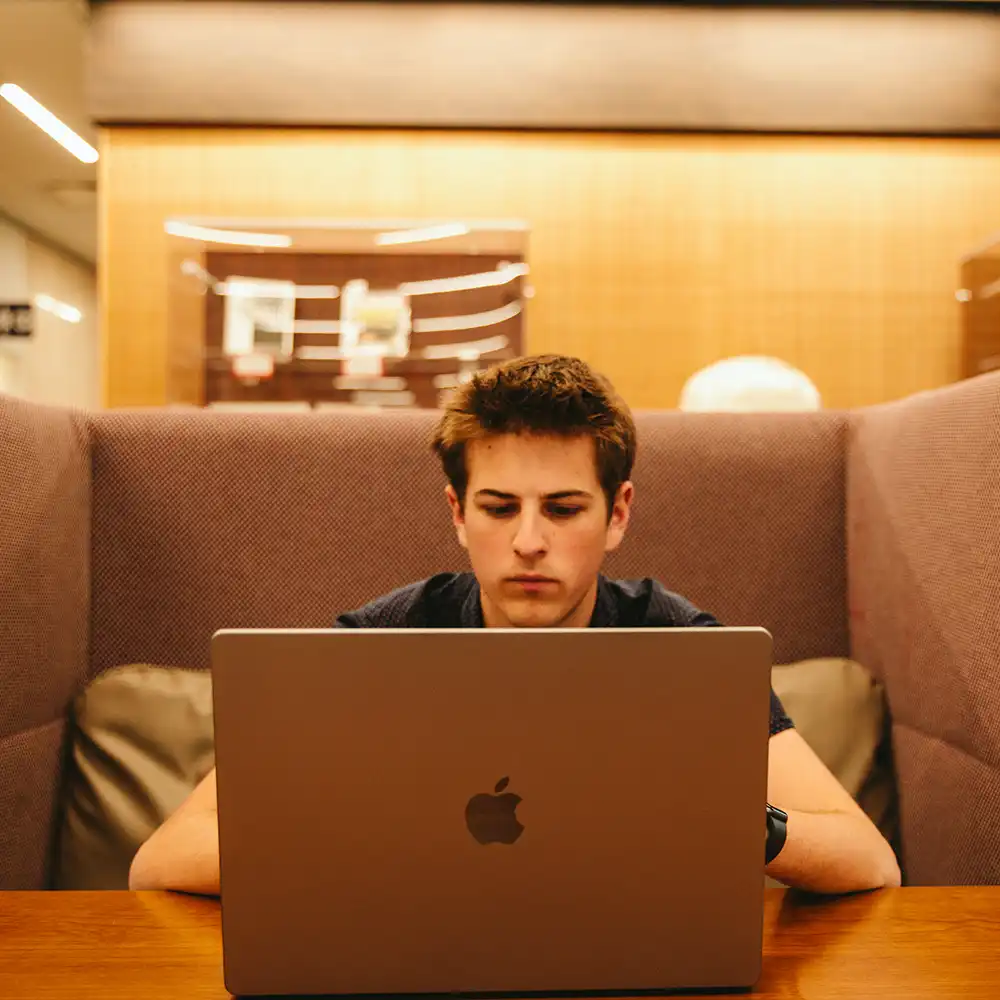 ​​SHSU Student working in a library on a laptop​.